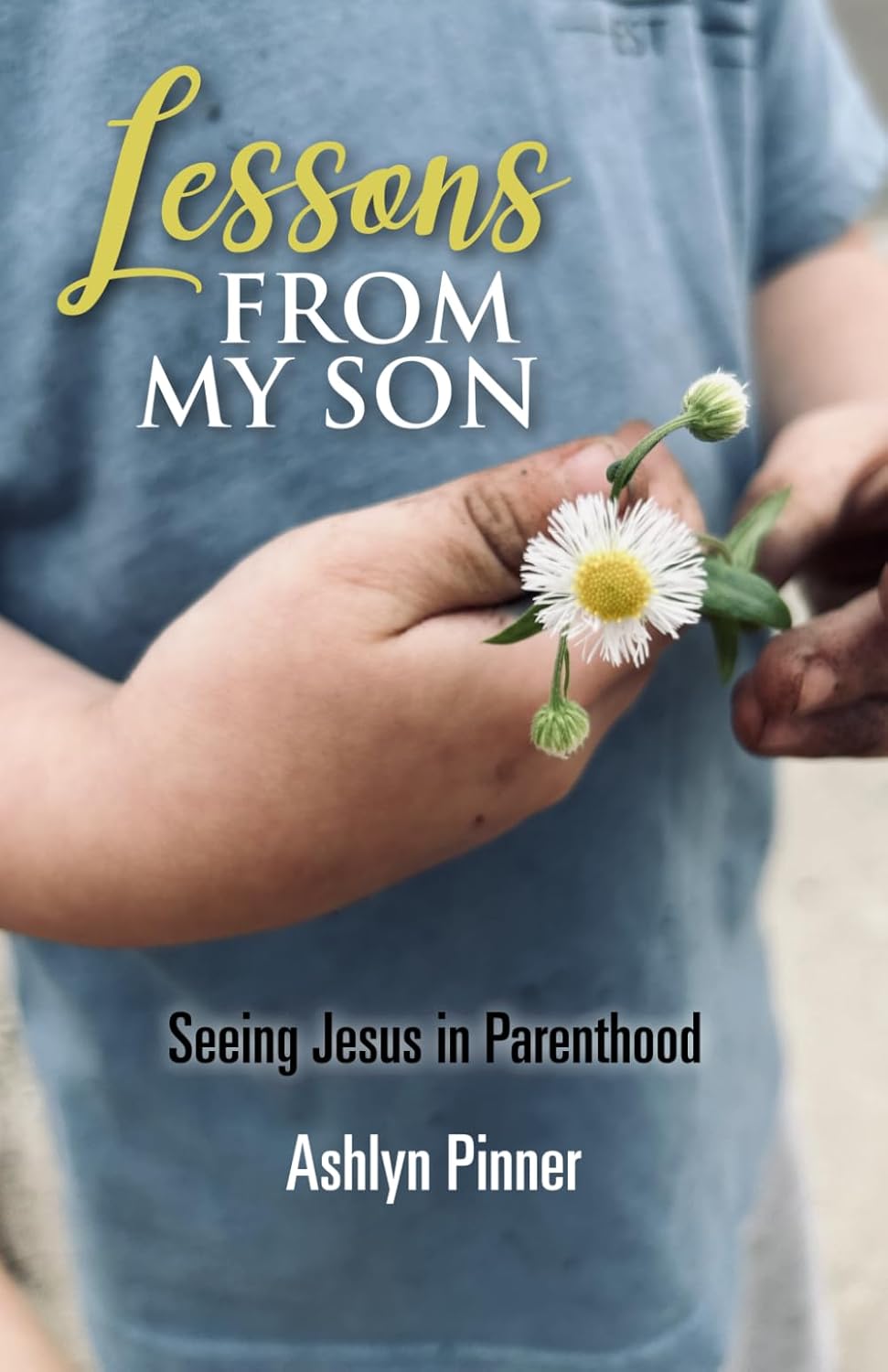 A child’s dirty hands gently hold a small white daisy. Overlaid text reads: Lessons From My Son: Seeing Jesus in Parenthood, Ashlyn Pinner.