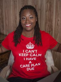 A woman with long braided hair, smiling and sitting in a chair, wears a red shirt that says I CANT KEEP CALM I HAVE A CARE PLAN DUE in white letters. The background features wood-paneled walls.