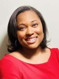 A woman with shoulder-length dark hair, wearing a bright red top, smiles warmly at the camera against a light-colored background.